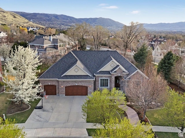 view of front of home with concrete driveway, an attached garage, a mountain view, and brick siding