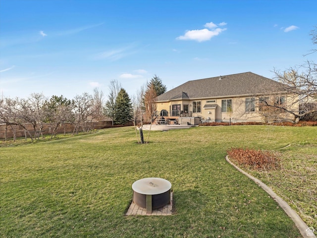back of property with fence, a wooden deck, a yard, and roof with shingles