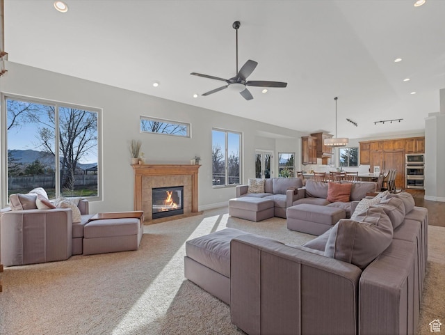 living area featuring recessed lighting, ceiling fan, a tiled fireplace, and a healthy amount of sunlight
