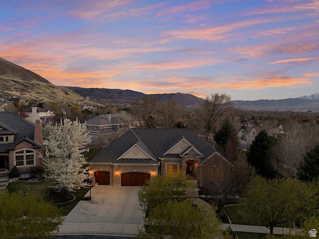 view of front facade with brick siding, driveway, a mountain view, and a garage