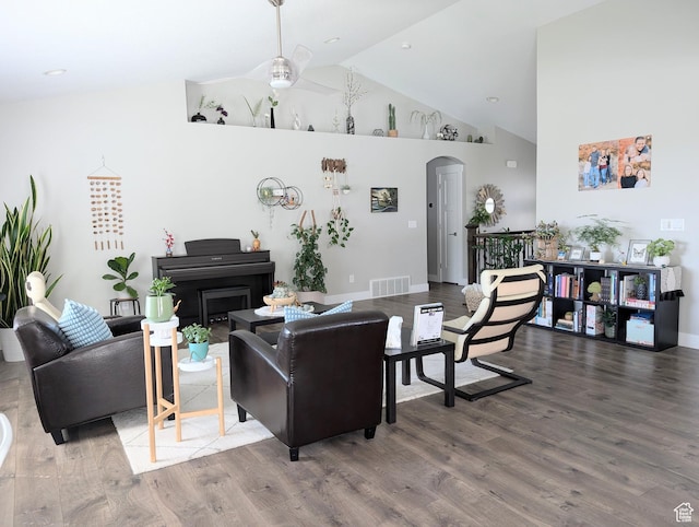 living room featuring arched walkways, wood finished floors, visible vents, and high vaulted ceiling