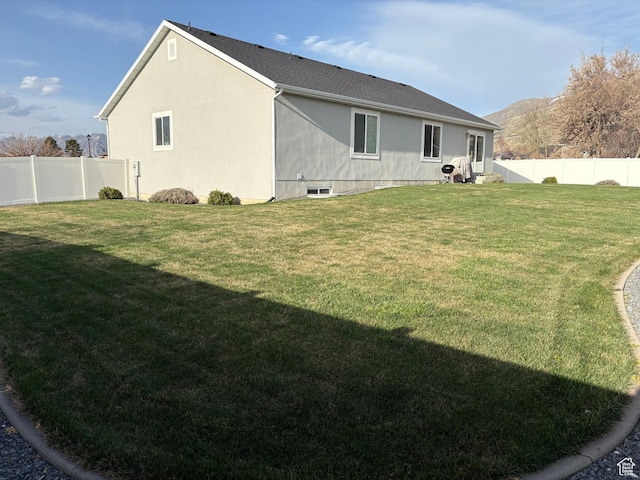 rear view of house with a lawn, a shingled roof, a fenced backyard, and a mountain view