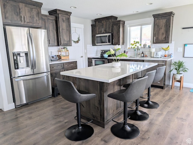 kitchen featuring a sink, tasteful backsplash, stainless steel appliances, and a breakfast bar area