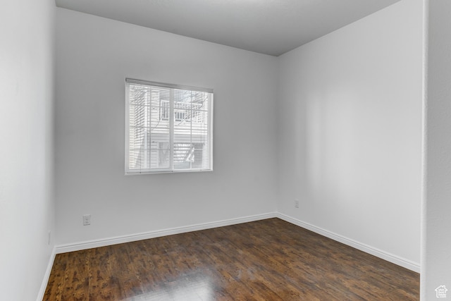 spare room featuring baseboards and dark wood-style floors