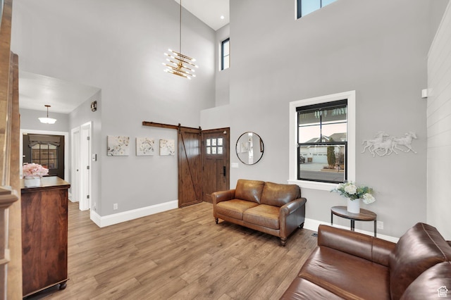2282 N 3430 W, Clinton, UT 84015 - living room featuring a towering ceiling, light wood-type flooring, a barn door, and plenty of natural light