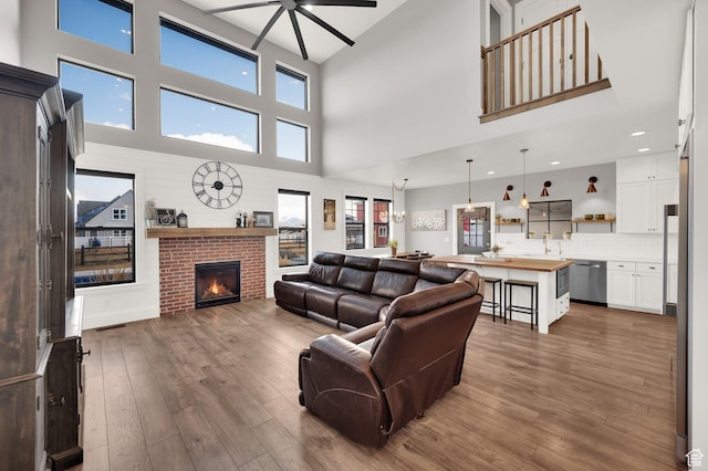 2282 N 3430 W, Clinton, UT 84015 - living room featuring ceiling fan, dark wood-type flooring, a high ceiling, a brick fireplace, and recessed lighting