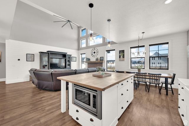 2282 N 3430 W, Clinton, UT 84015 - kitchen with wood counters, stainless steel microwave, dark wood-style flooring, white cabinetry, and decorative light fixtures