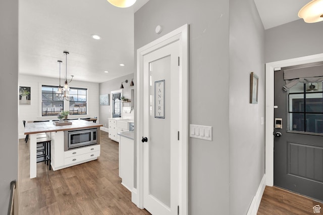 2282 N 3430 W, Clinton, UT 84015 - kitchen featuring stainless steel microwave, white cabinets, wood finished floors, hanging light fixtures, and a kitchen breakfast bar