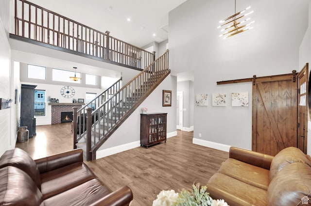 2282 N 3430 W, Clinton, UT 84015 - living area with a high ceiling, wood finished floors, a lit fireplace, a barn door, and stairway