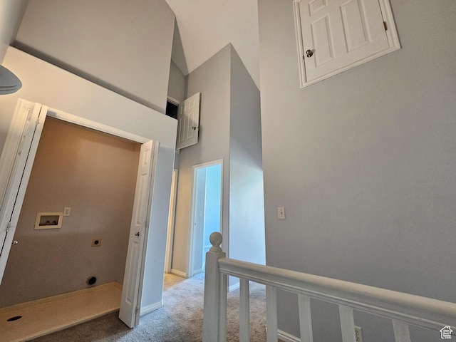 hall with a high ceiling, carpet flooring, wainscoting, and a decorative wall