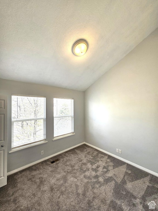 carpeted spare room with baseboards, visible vents, a textured ceiling, and vaulted ceiling