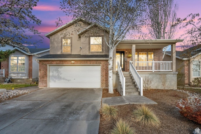 tri-level home featuring stairway, a porch, brick siding, an attached garage, and driveway