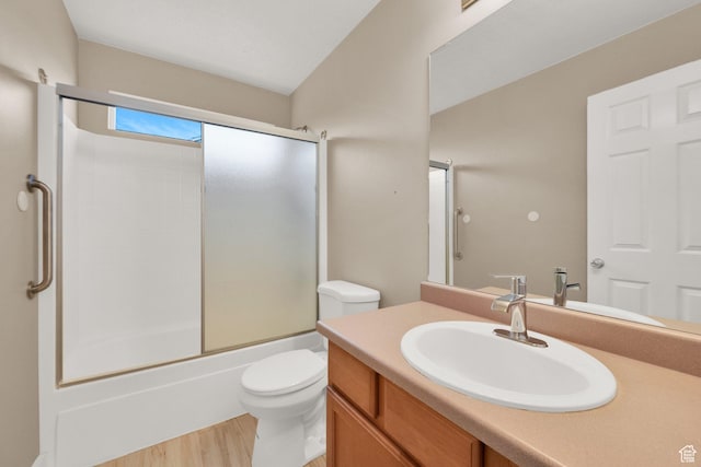 bathroom with bath / shower combo with glass door, vanity, toilet, and wood finished floors