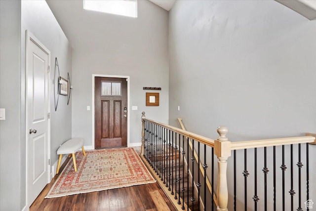 entrance foyer featuring a towering ceiling, baseboards, and wood finished floors