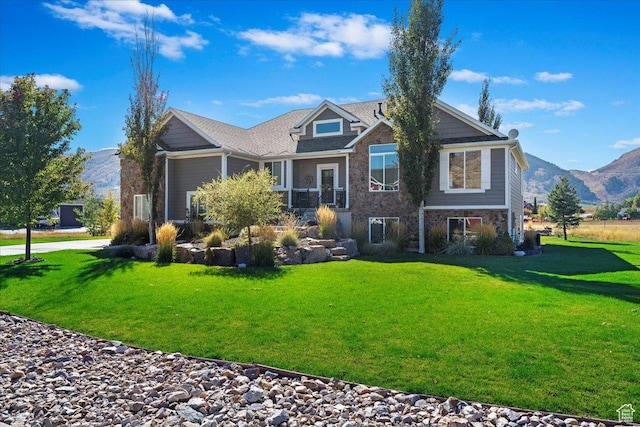 craftsman house featuring a mountain view, stone siding, and a front lawn