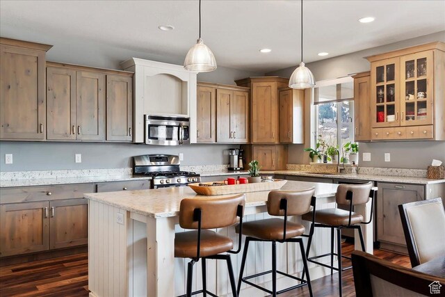 kitchen with glass insert cabinets, a breakfast bar, recessed lighting, stainless steel appliances, and a kitchen island