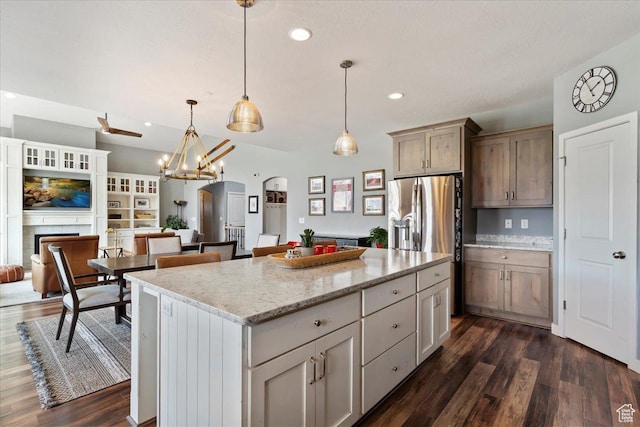 kitchen featuring a center island, an inviting chandelier, light stone counters, and dark wood-style floors
