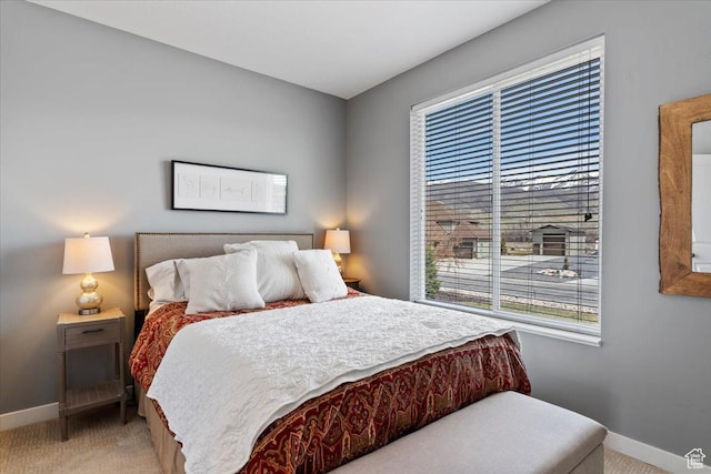 bedroom with baseboards and light colored carpet