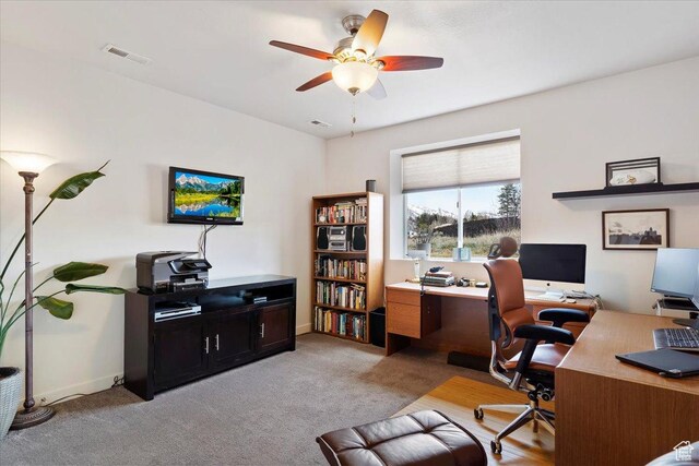 office area featuring light carpet, visible vents, baseboards, and a ceiling fan