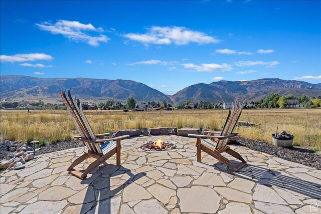 view of patio with a rural view, a mountain view, and an outdoor fire pit