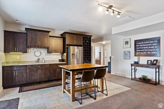 kitchen with baseboards, stainless steel fridge with ice dispenser, dark brown cabinets, and visible vents