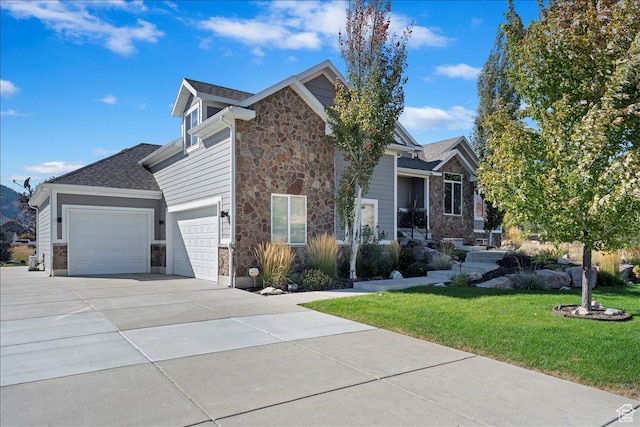 view of side of property featuring an attached garage, a yard, driveway, and stone siding