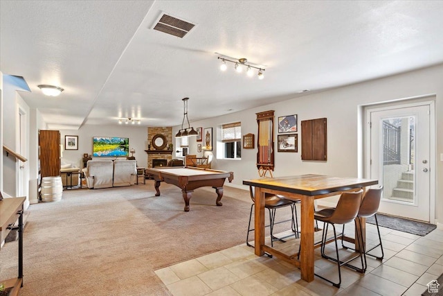 game room with pool table, a fireplace, a textured ceiling, visible vents, and light colored carpet