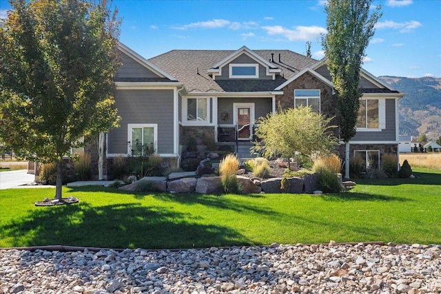 craftsman house with a front yard, stone siding, and a shingled roof