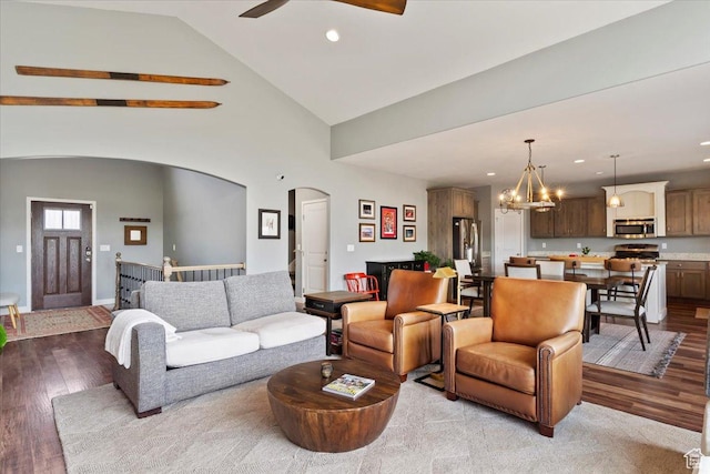 living room with arched walkways, recessed lighting, wood finished floors, ceiling fan with notable chandelier, and high vaulted ceiling