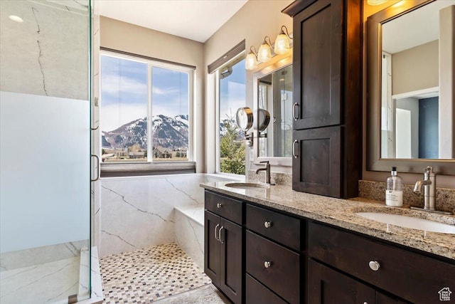 full bathroom with a mountain view, double vanity, a sink, and a marble finish shower