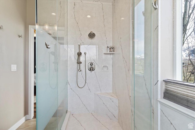 full bathroom with a marble finish shower and baseboards