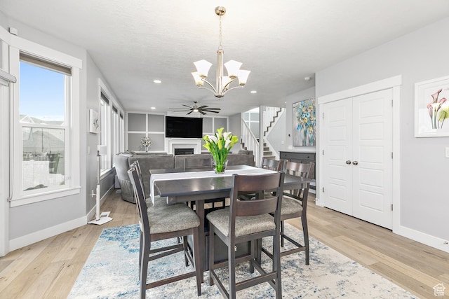 2913 S Puddle Ln, Saratoga Springs, UT 84045 - dining area with light wood-style flooring, baseboards, a fireplace, and stairs
