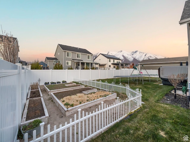 667 S Meade St, Mapleton, UT 84664 - yard at dusk featuring a trampoline, a fenced backyard, a mountain view, and a vegetable garden