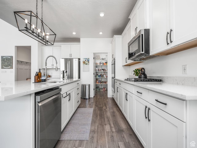 667 S Meade St, Mapleton, UT 84664 - kitchen featuring appliances with stainless steel finishes, white cabinets, a center island with sink, dark wood finished floors, and a sink