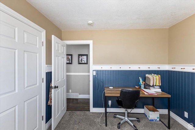 carpeted office featuring visible vents, baseboards, and a textured ceiling