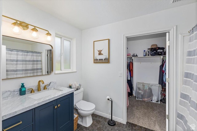 full bath with toilet, vanity, baseboards, and a spacious closet