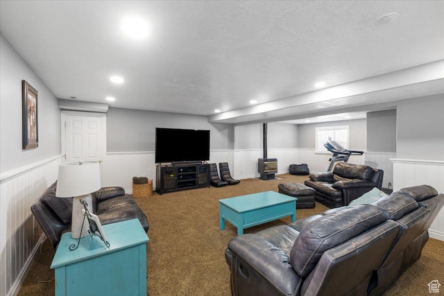carpeted living area featuring a textured ceiling, recessed lighting, and a wainscoted wall