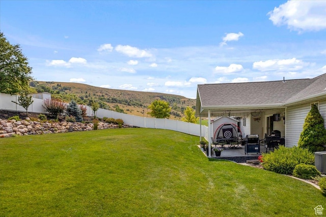 view of yard with a mountain view, a patio area, and a fenced backyard