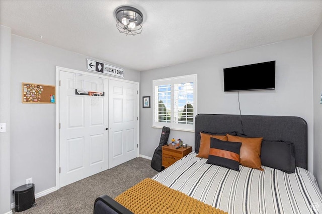 bedroom with a textured ceiling, a closet, baseboards, and carpet floors
