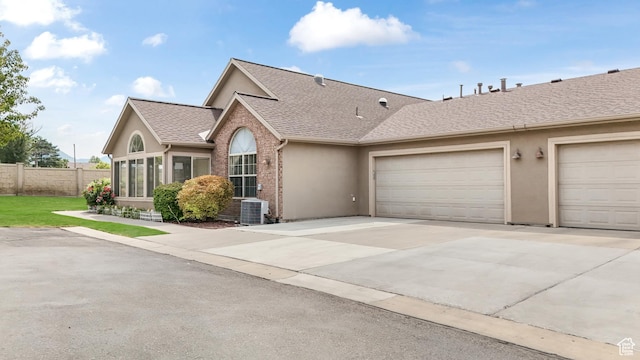 ranch-style home featuring fence, a shingled roof, concrete driveway, stucco siding, and a garage