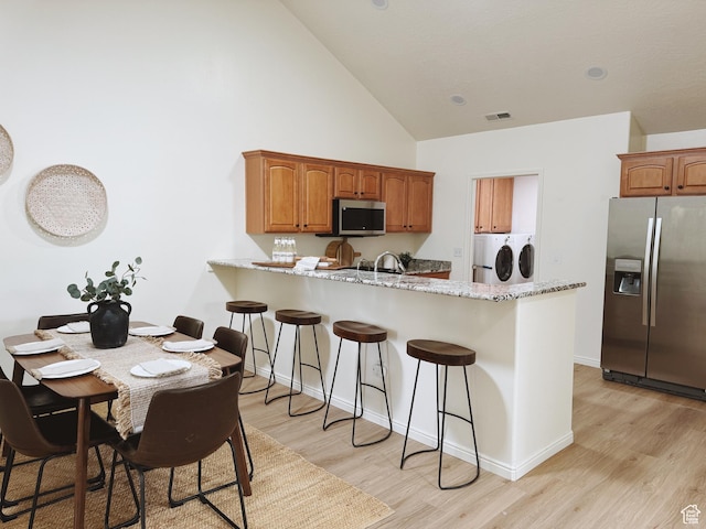 374 N 1100 E Unit F3, Lehi, UT 84043 - kitchen featuring high vaulted ceiling, a breakfast bar area, washer and dryer, stainless steel appliances, and visible vents