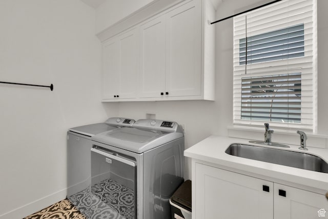 laundry room with baseboards, a sink, cabinet space, washing machine and clothes dryer, and tile patterned flooring