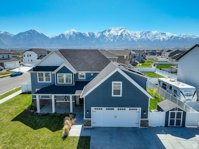 view of front of home featuring a mountain view, stone siding, fence, and an attached garage