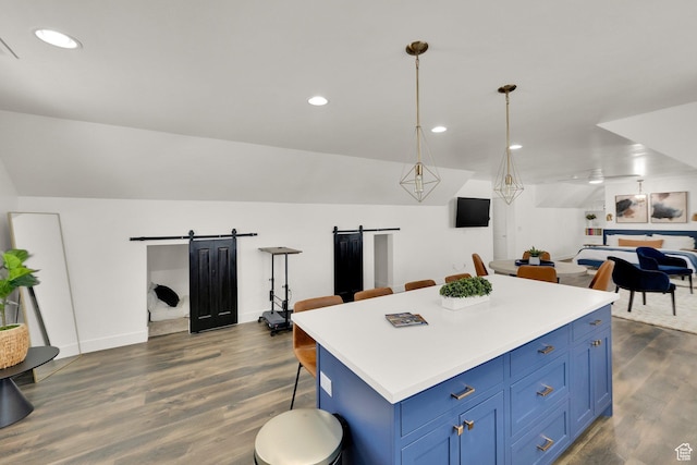 kitchen featuring a breakfast bar, open floor plan, dark wood-type flooring, a barn door, and blue cabinets
