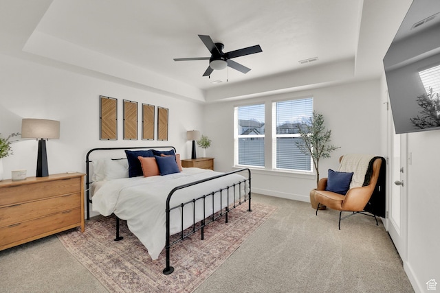 carpeted bedroom featuring a tray ceiling, baseboards, multiple windows, and visible vents