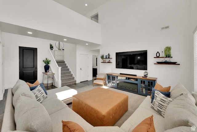 living area featuring recessed lighting, a towering ceiling, and stairs