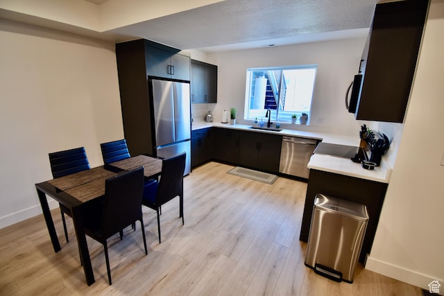 kitchen featuring a sink, light wood-type flooring, light countertops, and appliances with stainless steel finishes