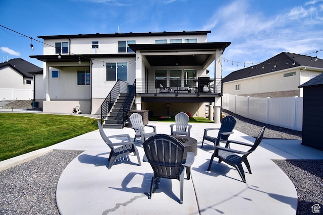 rear view of house with a patio area, a fire pit, stucco siding, and fence