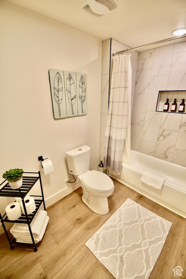 full bath with visible vents, toilet, wood finished floors, shower / tub combo, and baseboards