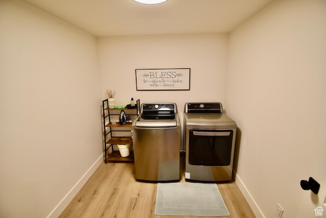 clothes washing area featuring washer and dryer, laundry area, baseboards, and light wood-type flooring